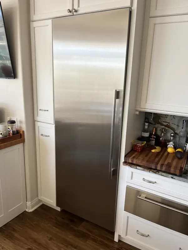 Panel-ready built-in column refrigerator installed flush with white kitchen cabinetry