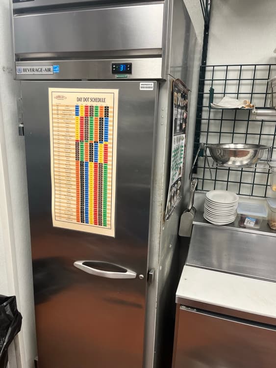 Commercial kitchen in Tampa with reach-in refrigeration and a food temperature chart on the wall