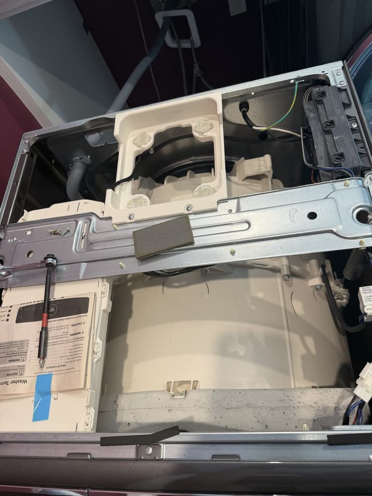 Electrolux front-load washer opened from the top for E11 diagnostics with the tub and frame brace exposed and the factory tech sheet visible