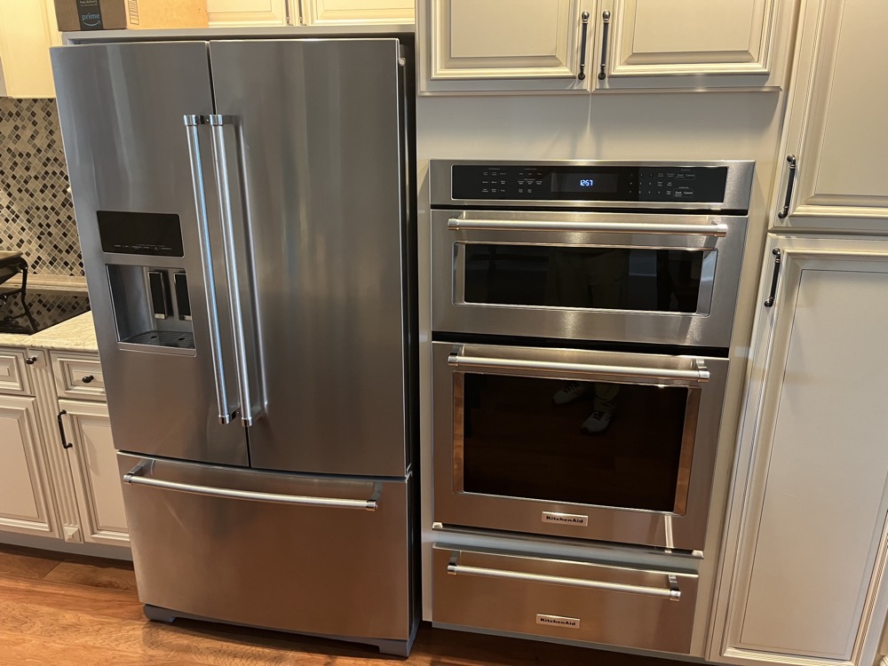 French-door refrigerator paired with a KitchenAid wall oven, the builder package common in newer Lutz subdivisions