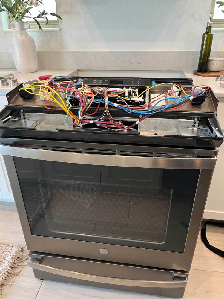 GE slide-in induction range pulled out with the top cover removed and induction coil wiring exposed, Morrison Ave, South Tampa, FL 33629