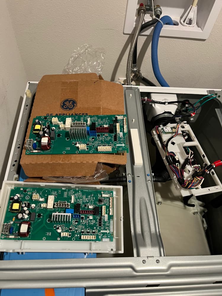 GE washer with the top panel open, replacement control board in its box beside the old board, S MacDill Ave, South Tampa, FL 33629