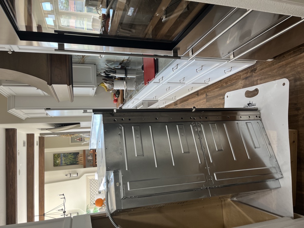 Slide-in range pulled from the counter with the back panel opened for repair in a Tampa Bay kitchen