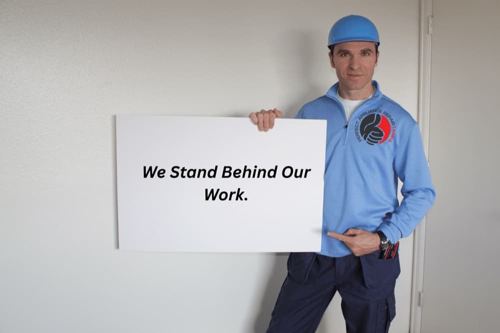 Perfect Appliance Repair Tampa technician holding a We Stand Behind Our Work sign