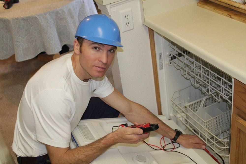 Mark, the owner-technician at Perfect Appliance Repair Tampa, testing a built-in dishwasher with a meter under the counter