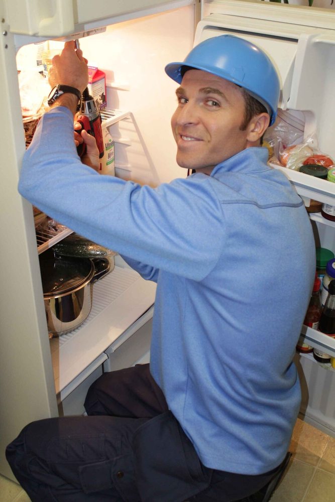 Owner-technician working inside a refrigerator during a same-day appliance repair in Tampa