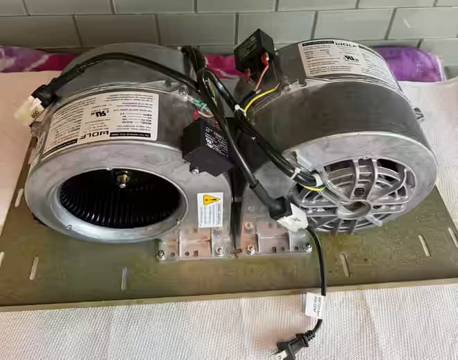 Two new Wolf 814784 internal blowers with run capacitors mounted on the hood's blower plate, each tagged 600 CFM