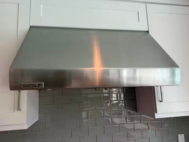 Wolf pro wall hood in brushed stainless steel with the Wolf badge, seen from below after the blower replacement